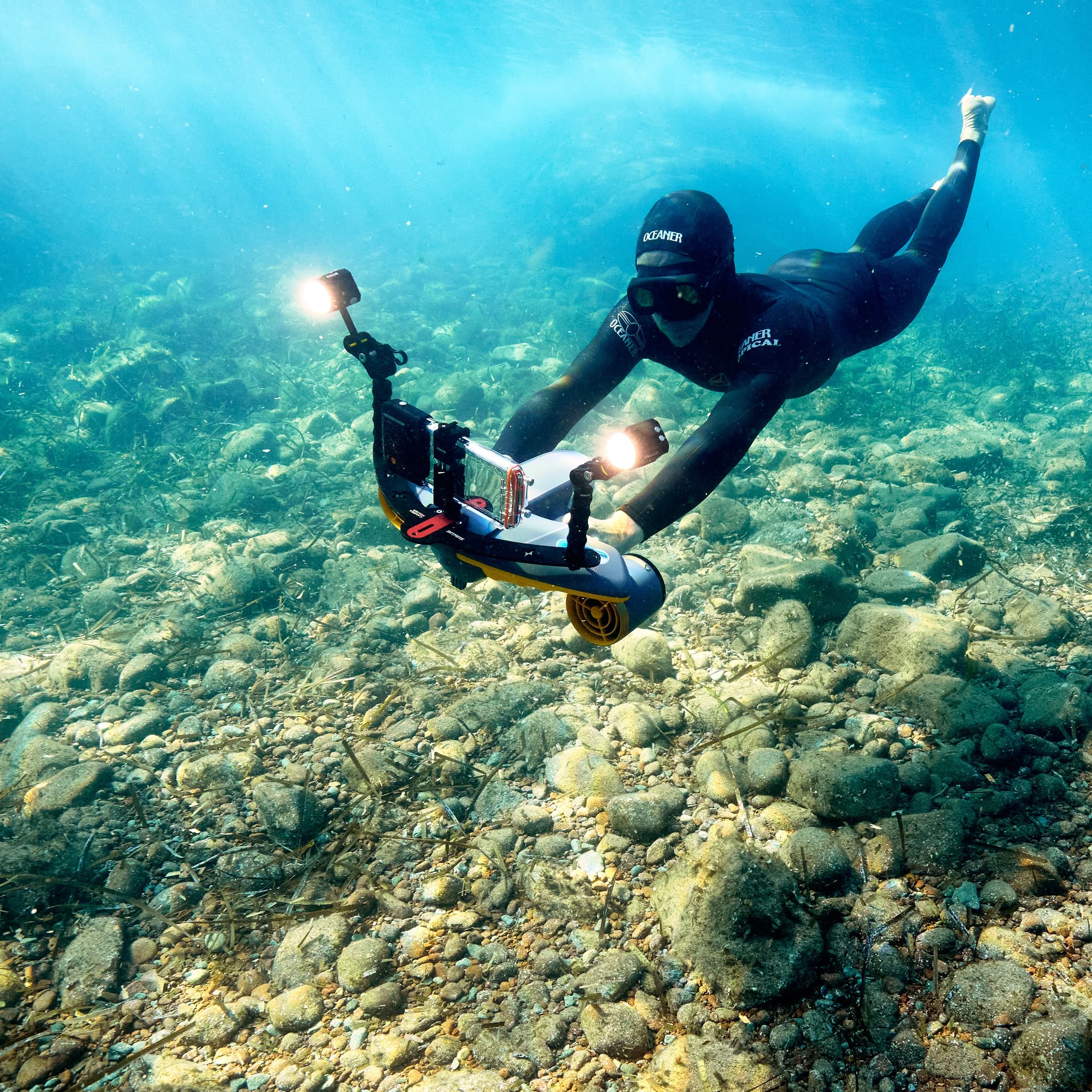 Diver using Sublue underwater scooter with smartphone for underwater photography.