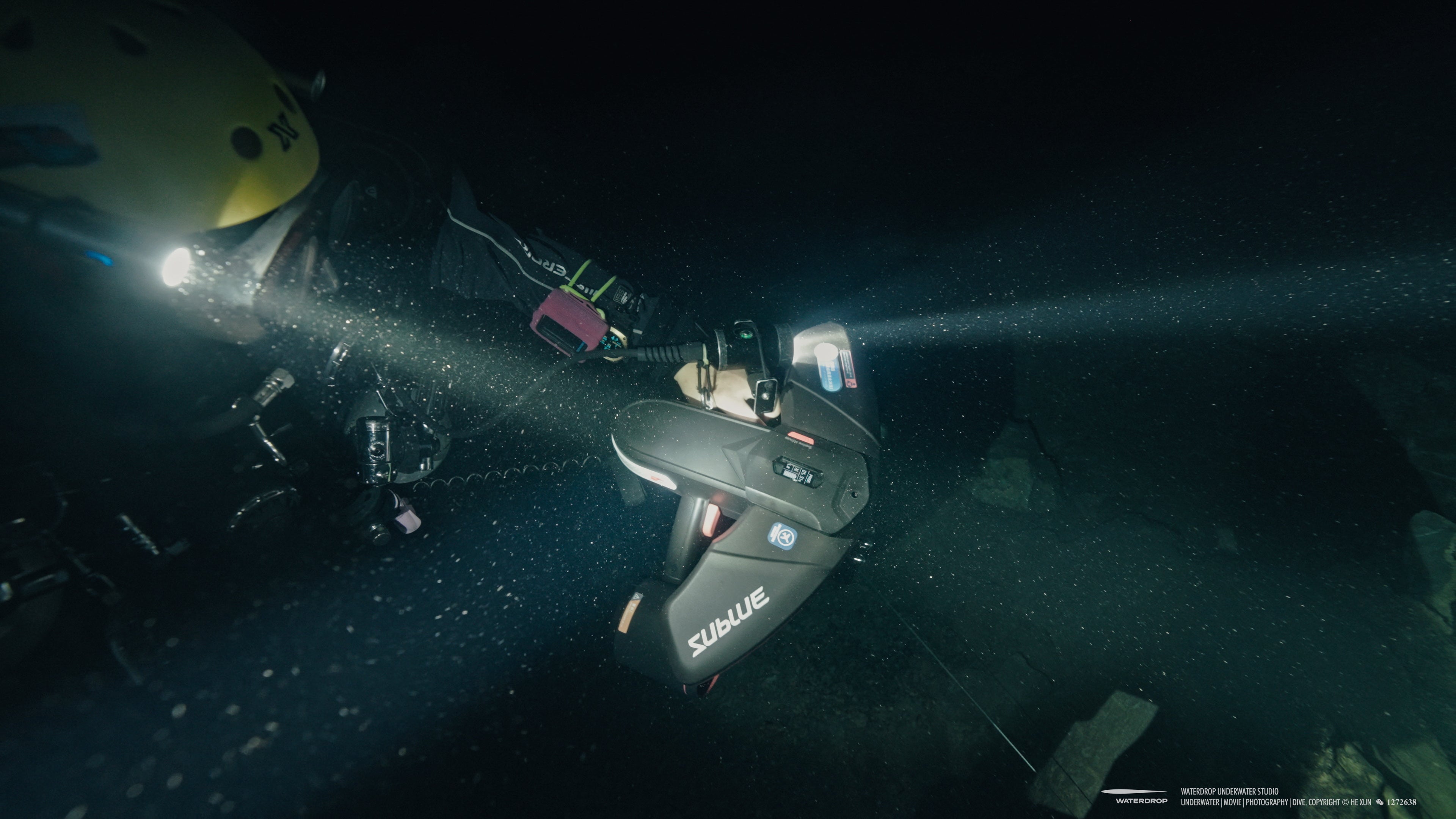 Diver using Navbow+ underwater scooter with powerful lights in dark waters.