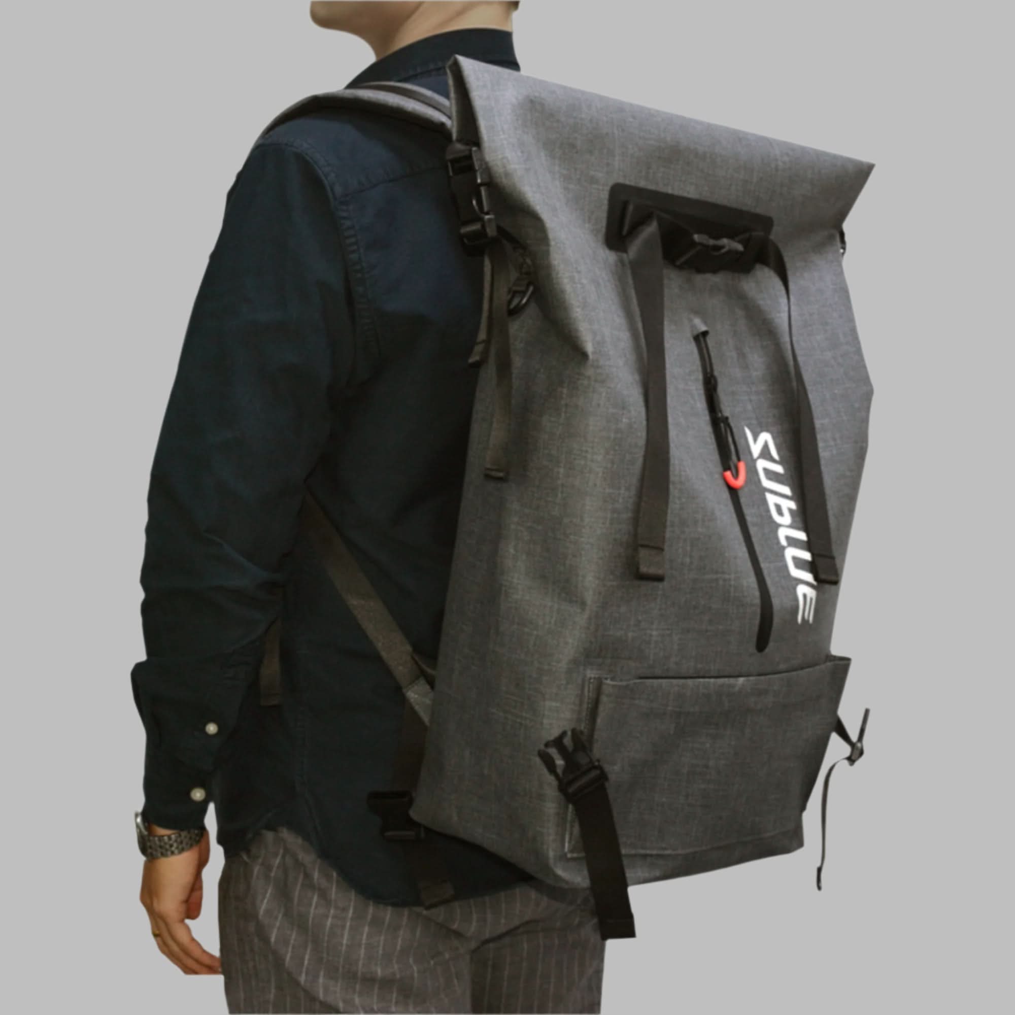 Person wearing grey Sublue waterproof backpack with roll-top closure and side pockets.