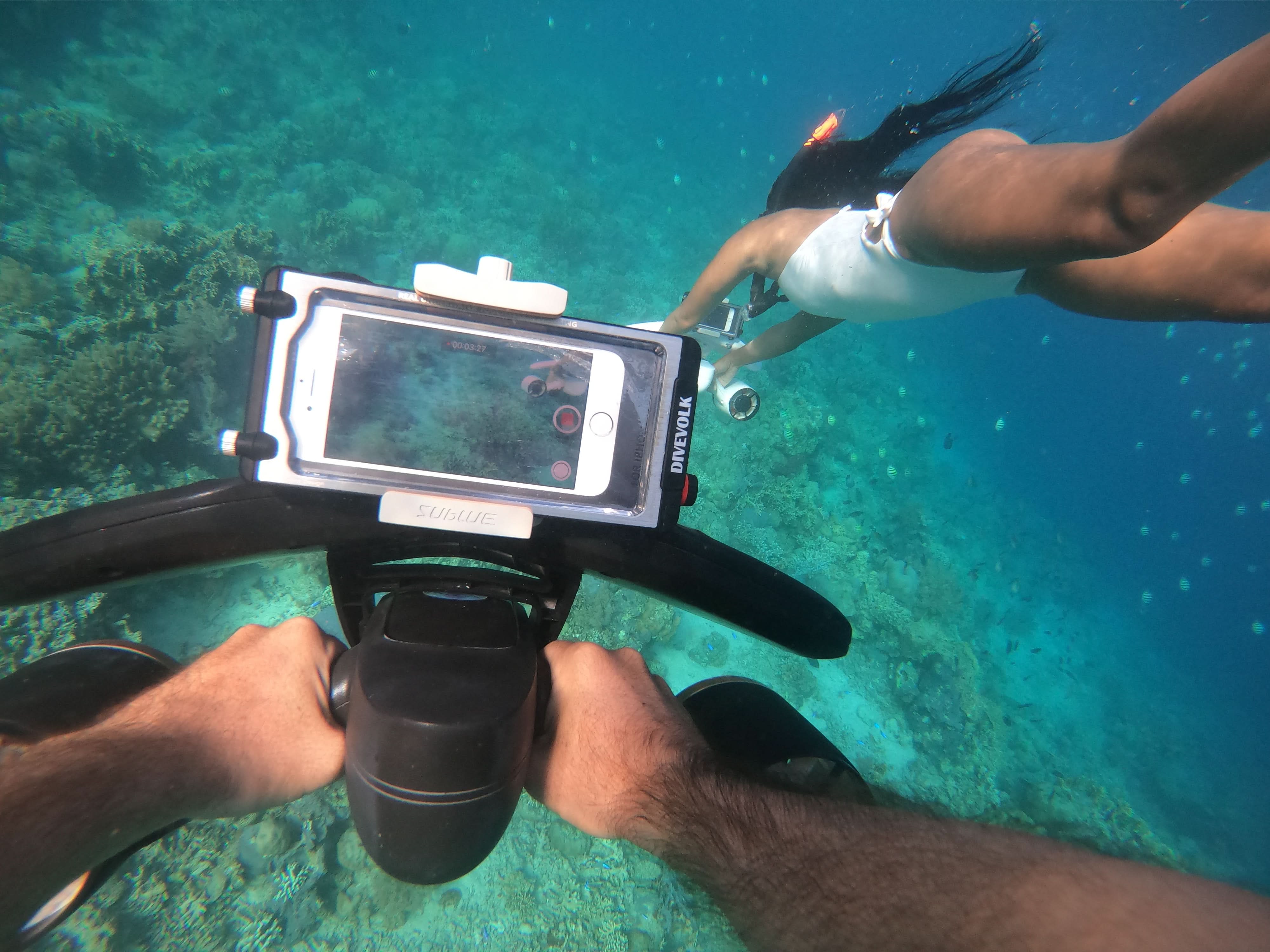 Diver using SUBLUE MixPro underwater scooter with smartphone mount for capturing underwater moments.