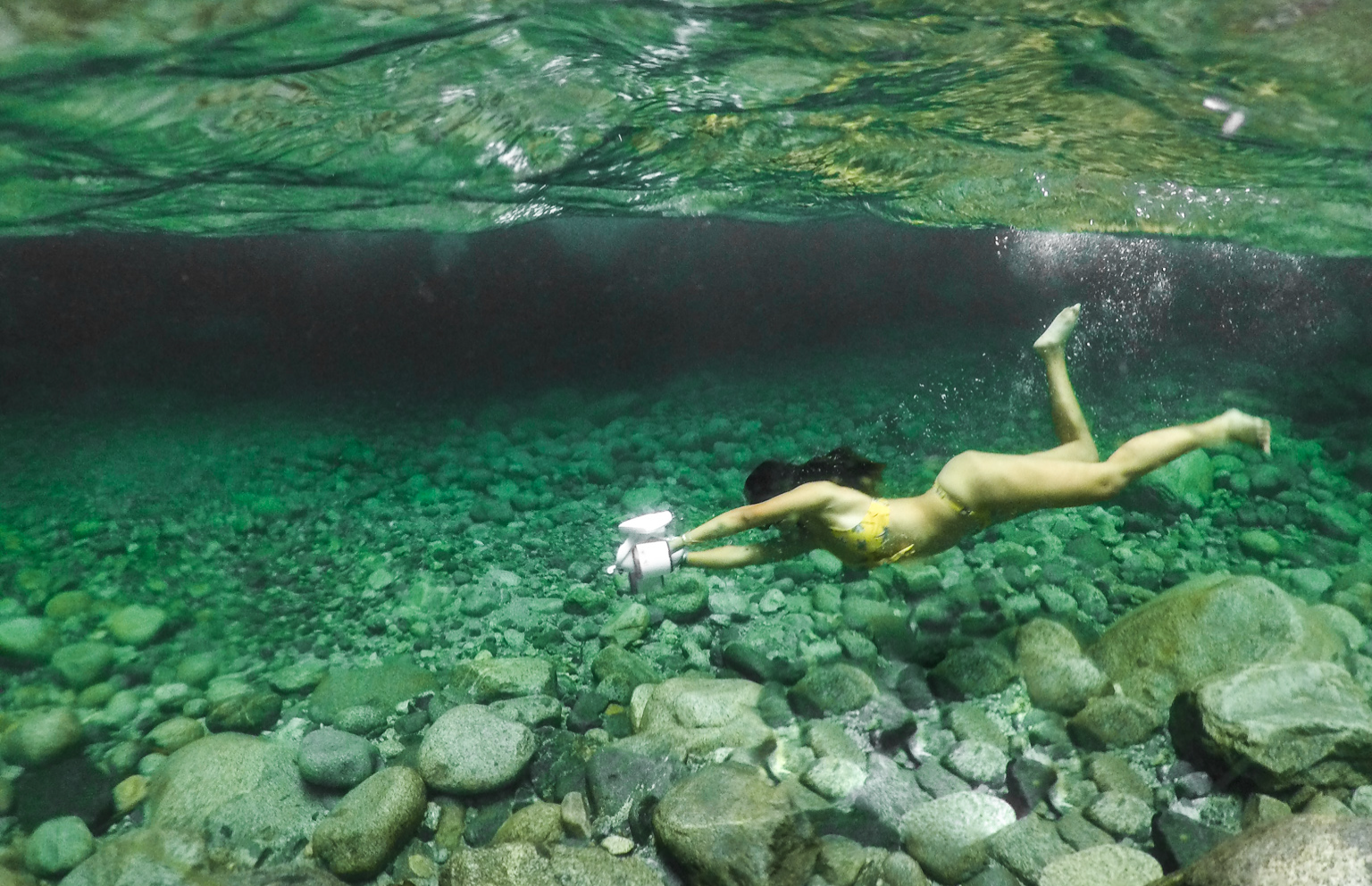 A scuba diver with a camera exploring a coral reef underwater.