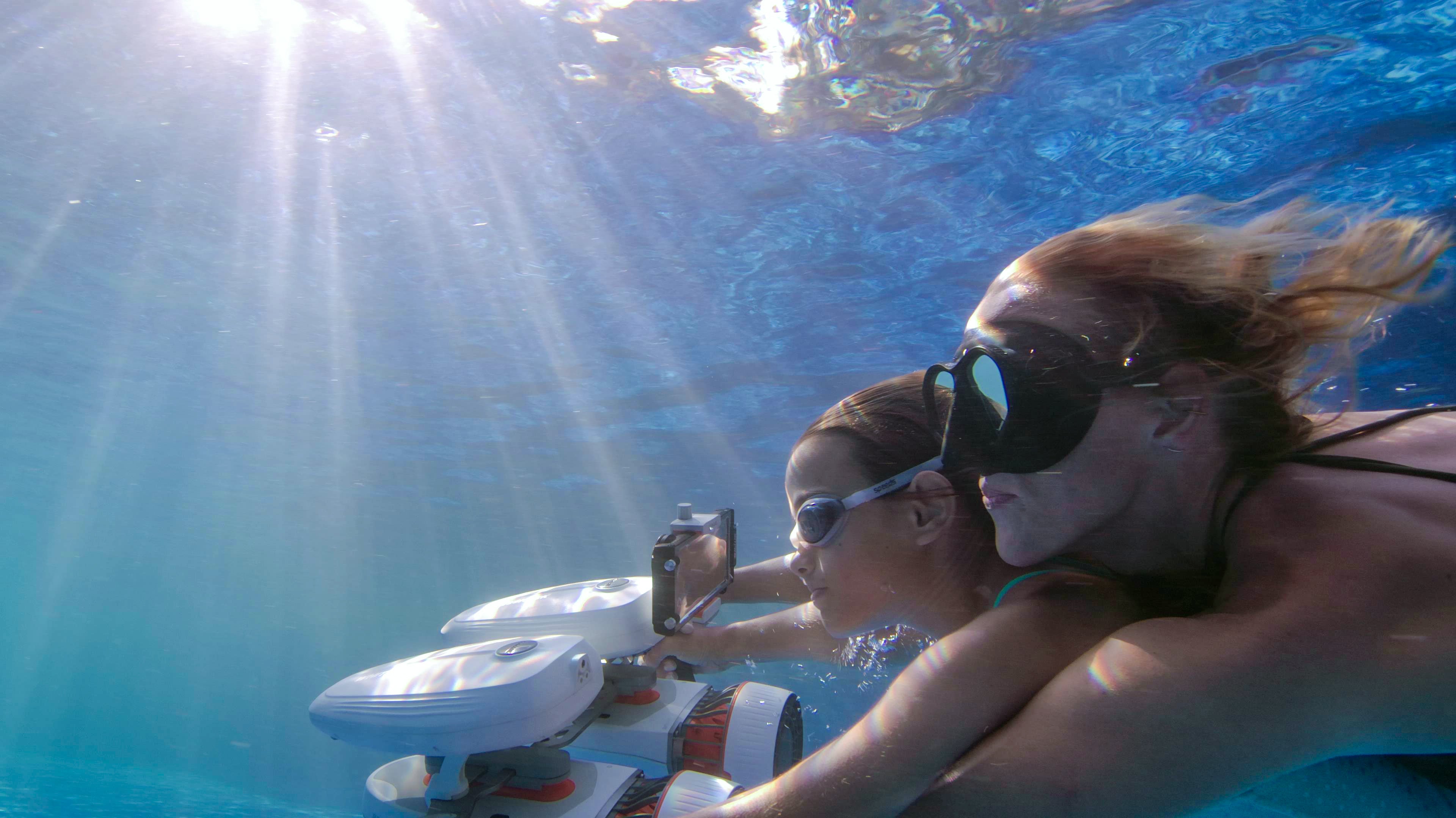 Two divers using Whiteshark underwater scooter to capture photos underwater.