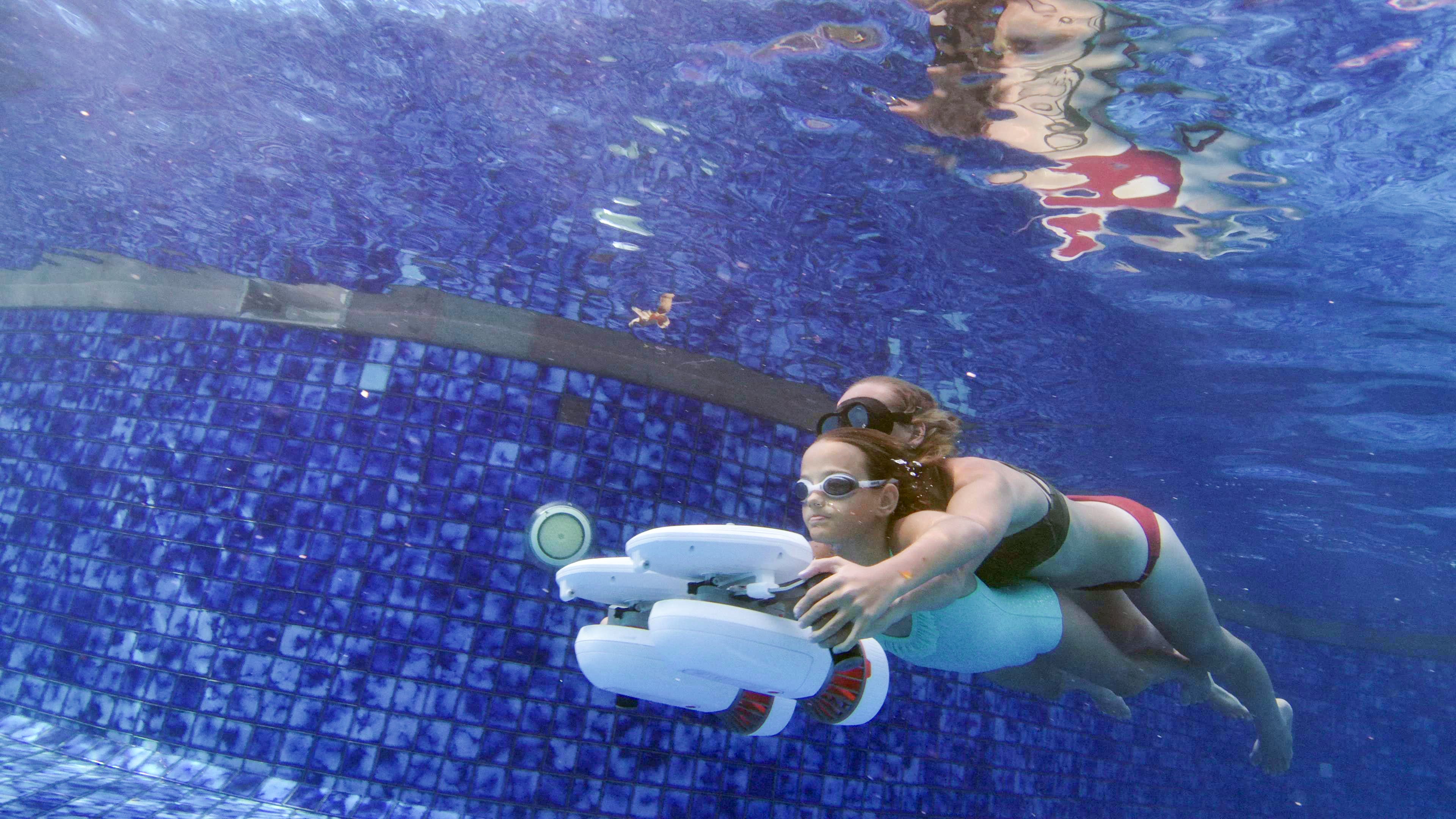 Diver using Tini Floater with underwater scooter in a pool.