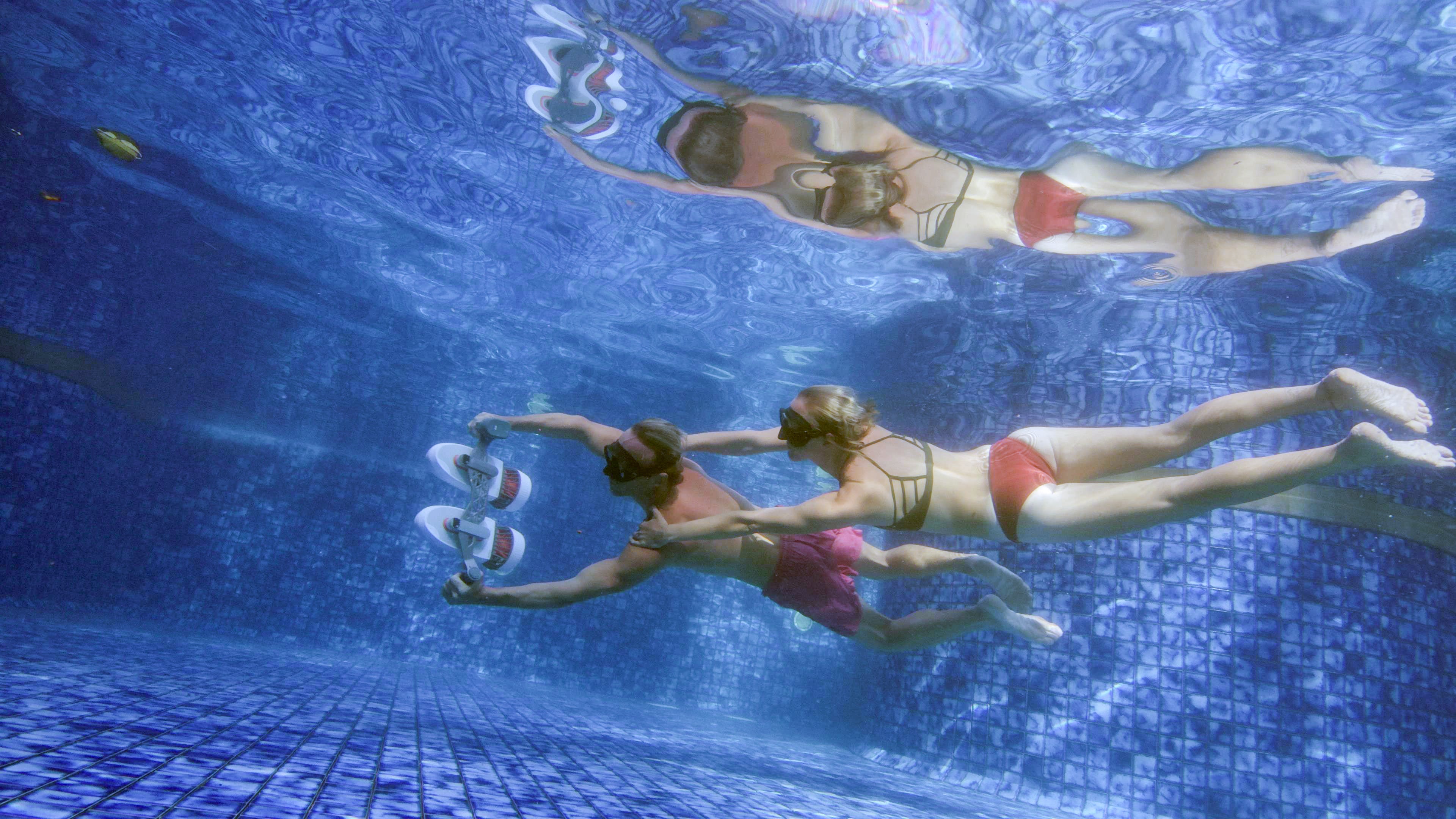 Swimmers using Tini Double-Engine Support Handle for underwater propulsion.