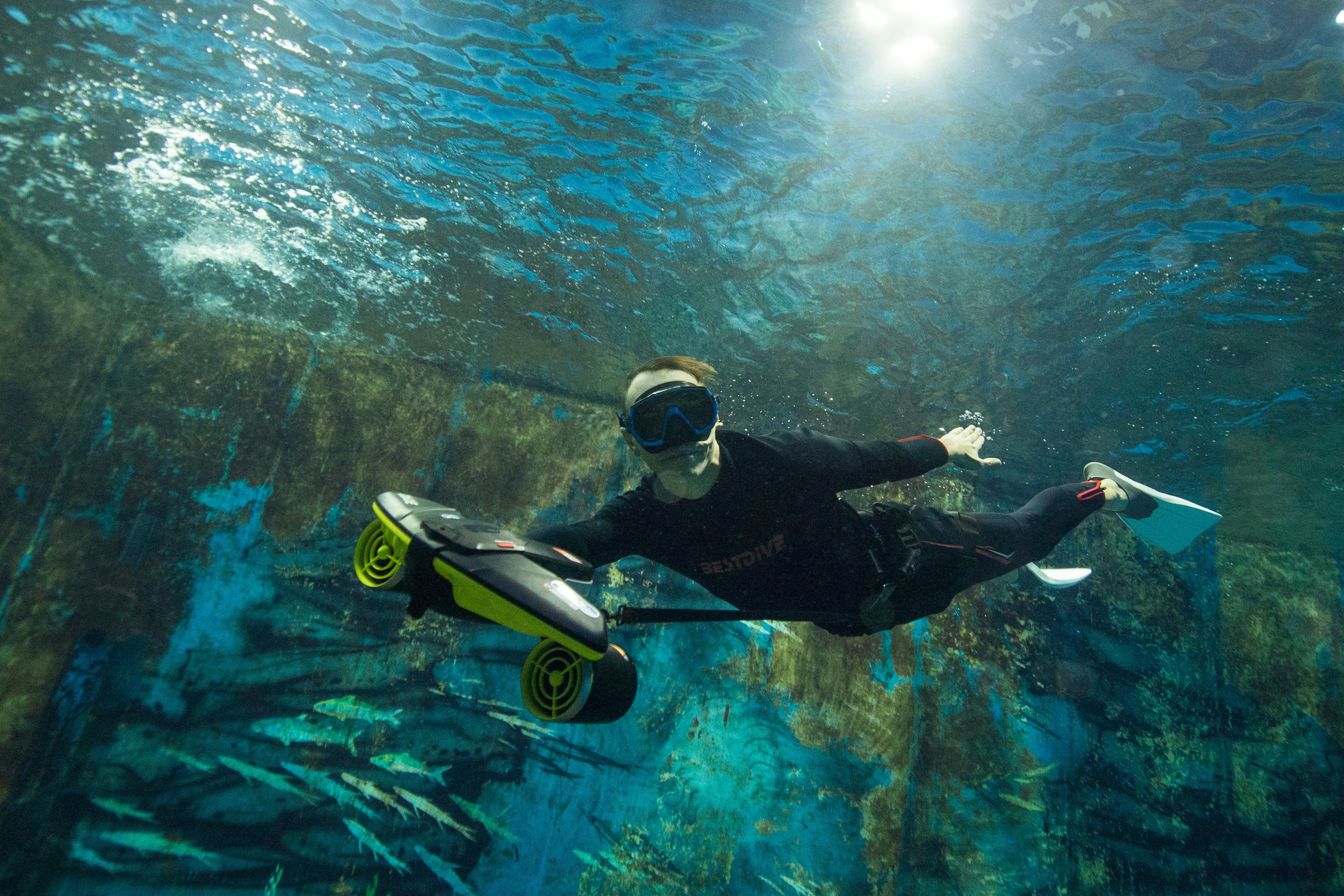 Diver using Sublue underwater scooter in clear water for underwater exploration.