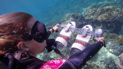 Diver using Tini Double-Engine Support Handle for underwater exploration among coral.