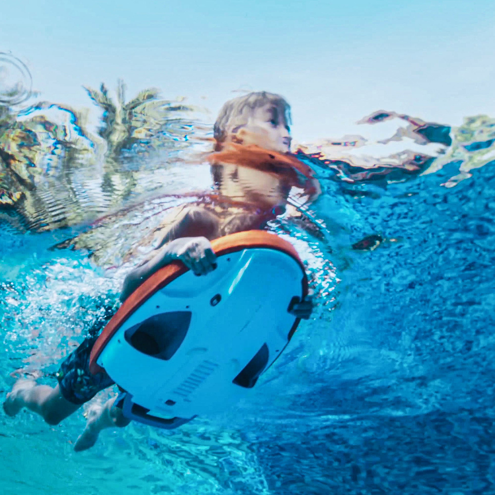 Child using SUBLUE Swii Electronic Kickboard underwater in a blue pool.