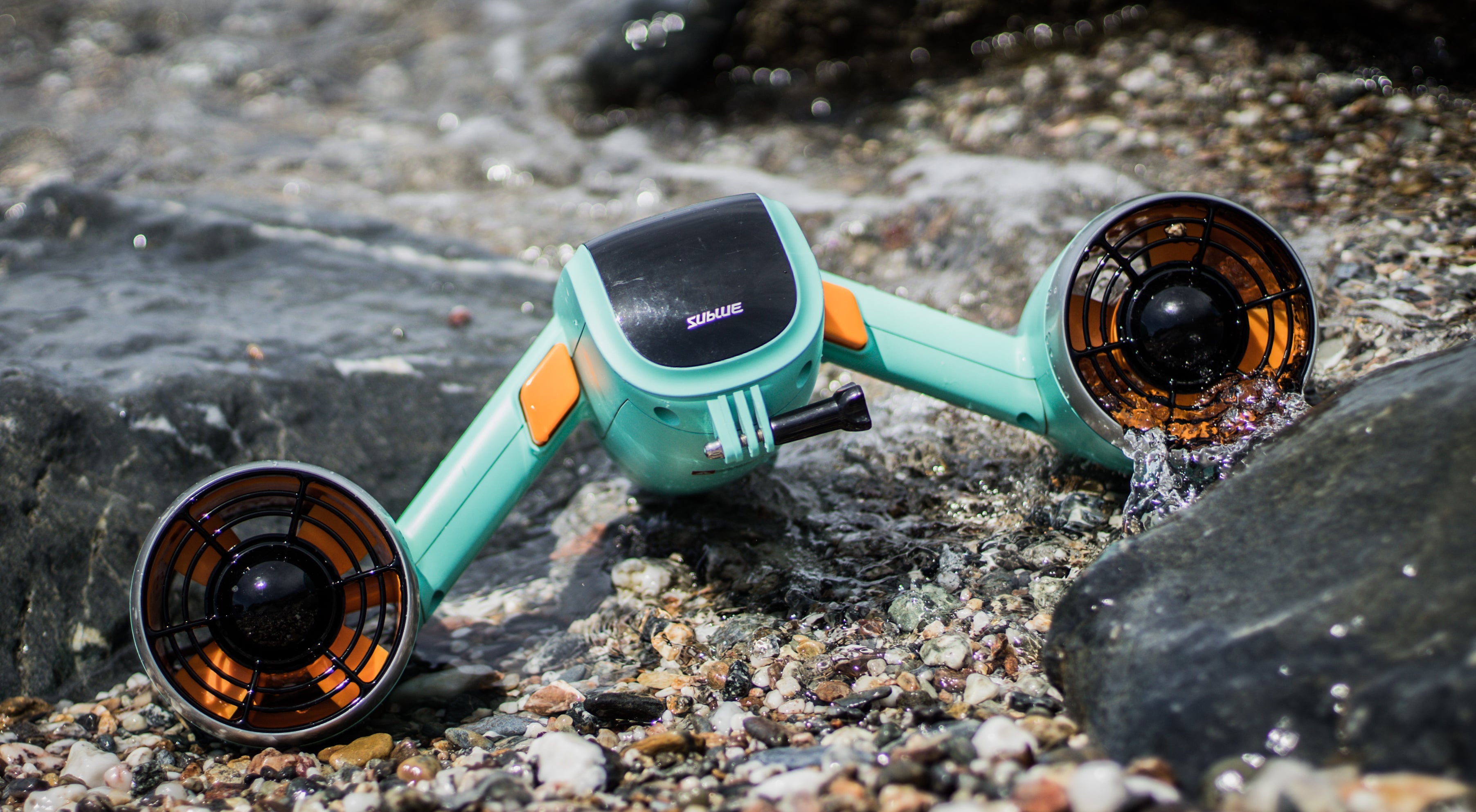 Sublue Mix underwater scooter featuring teal design near rocky shoreline.