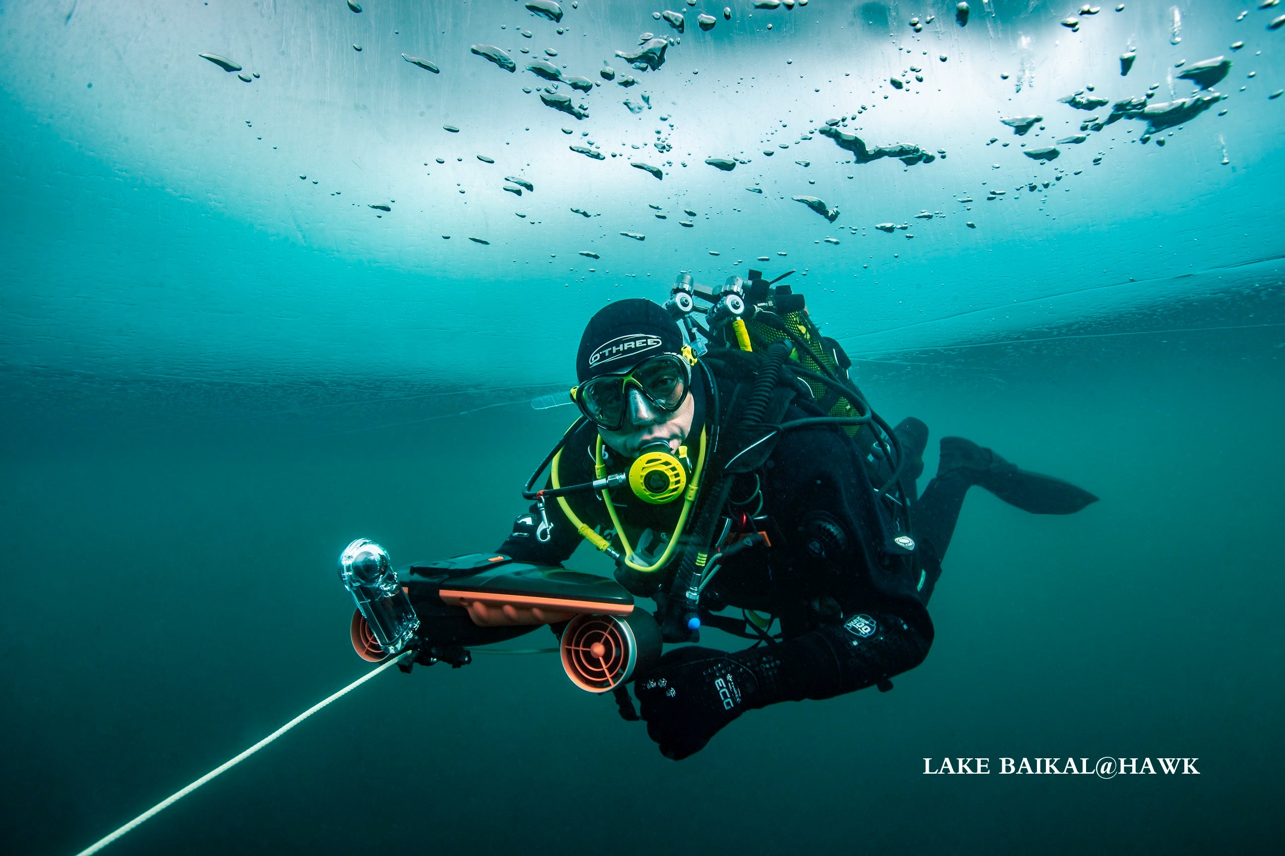 Diver using SUBLUE Navbow scooter in clear water beneath ice, showcasing underwater exploration.