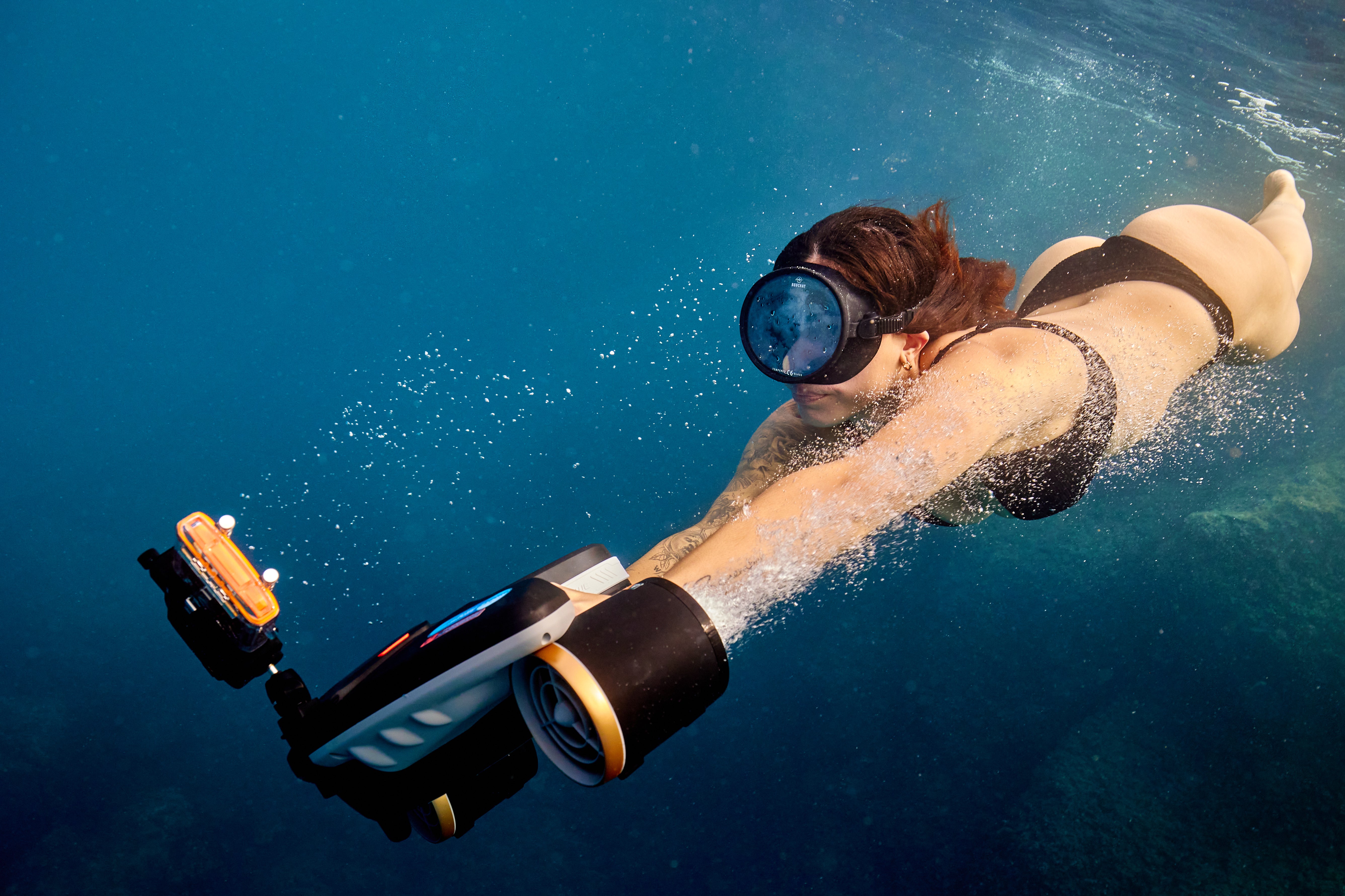 Swimmer using SUBLUE MixPro underwater scooter in clear blue water.