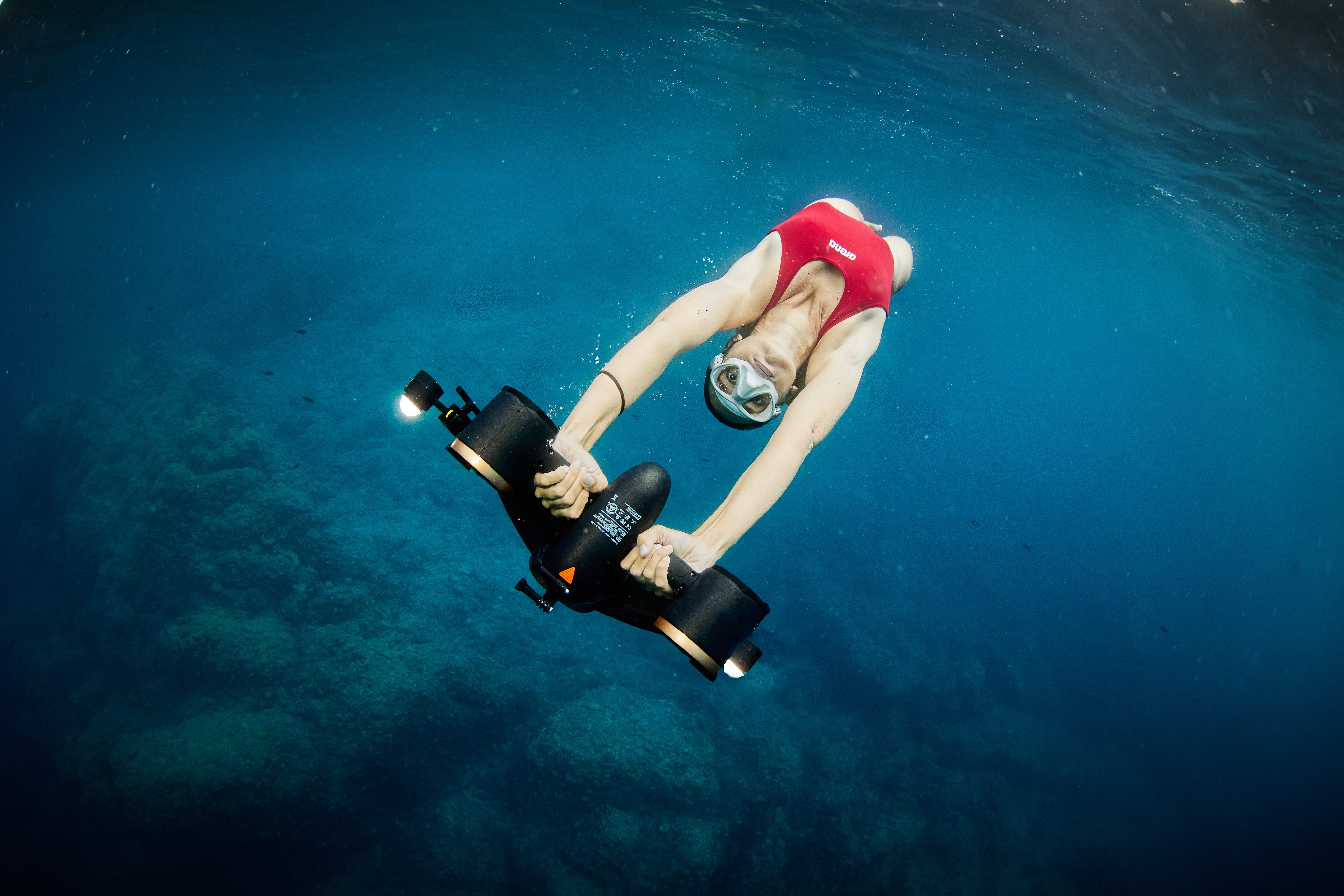 Swimmer using SUBLUE MixPro underwater scooter in clear blue water.