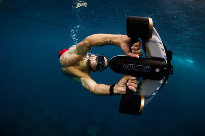 Diver in red swimsuit using SUBLUE Navbow+ scooter underwater with dual propellers.