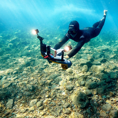 Diver using Sublue underwater scooter with smartphone for underwater photography.