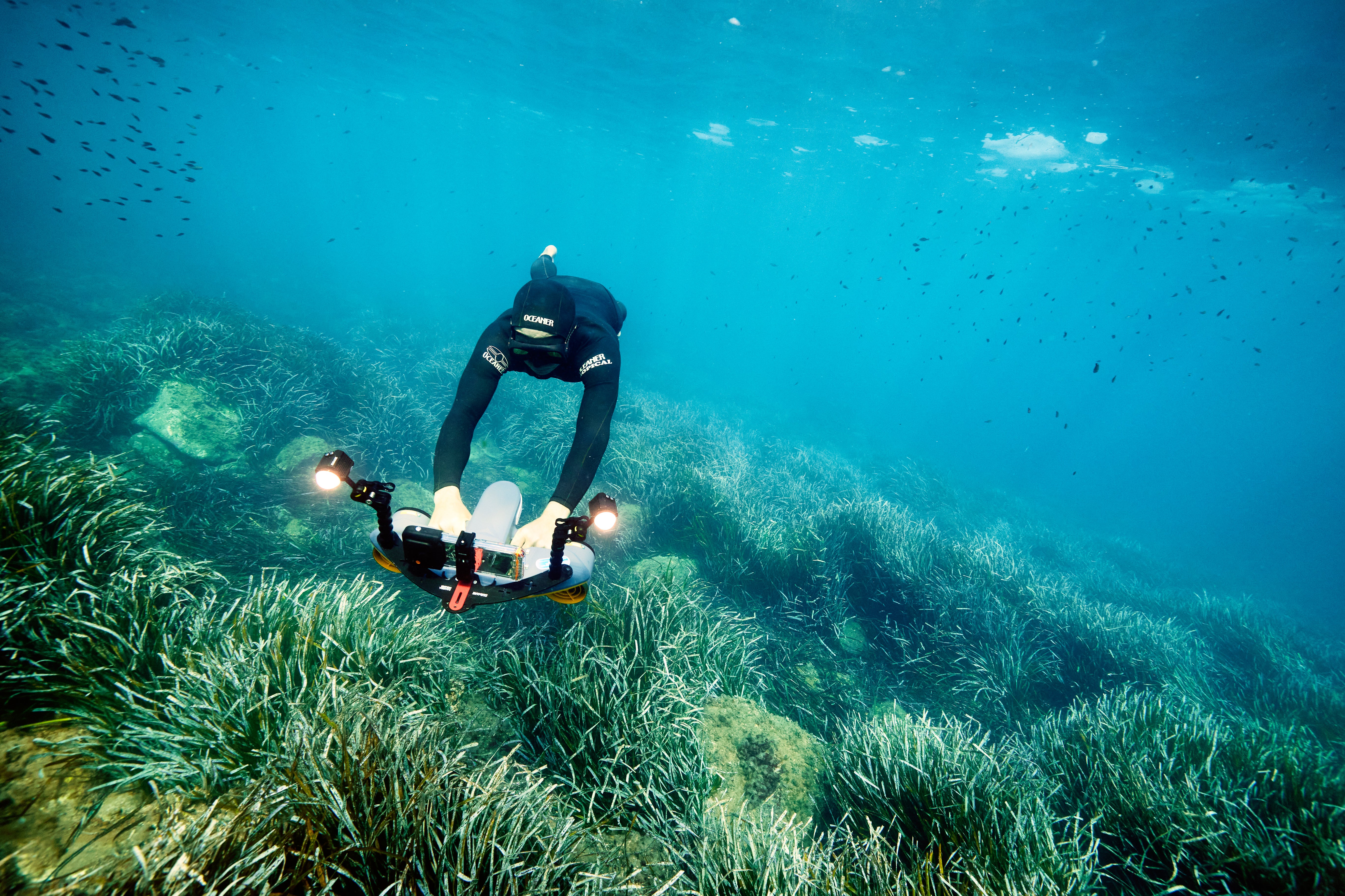 Diver with Sublue MixPro scooter and LED lights navigating seagrass underwater.