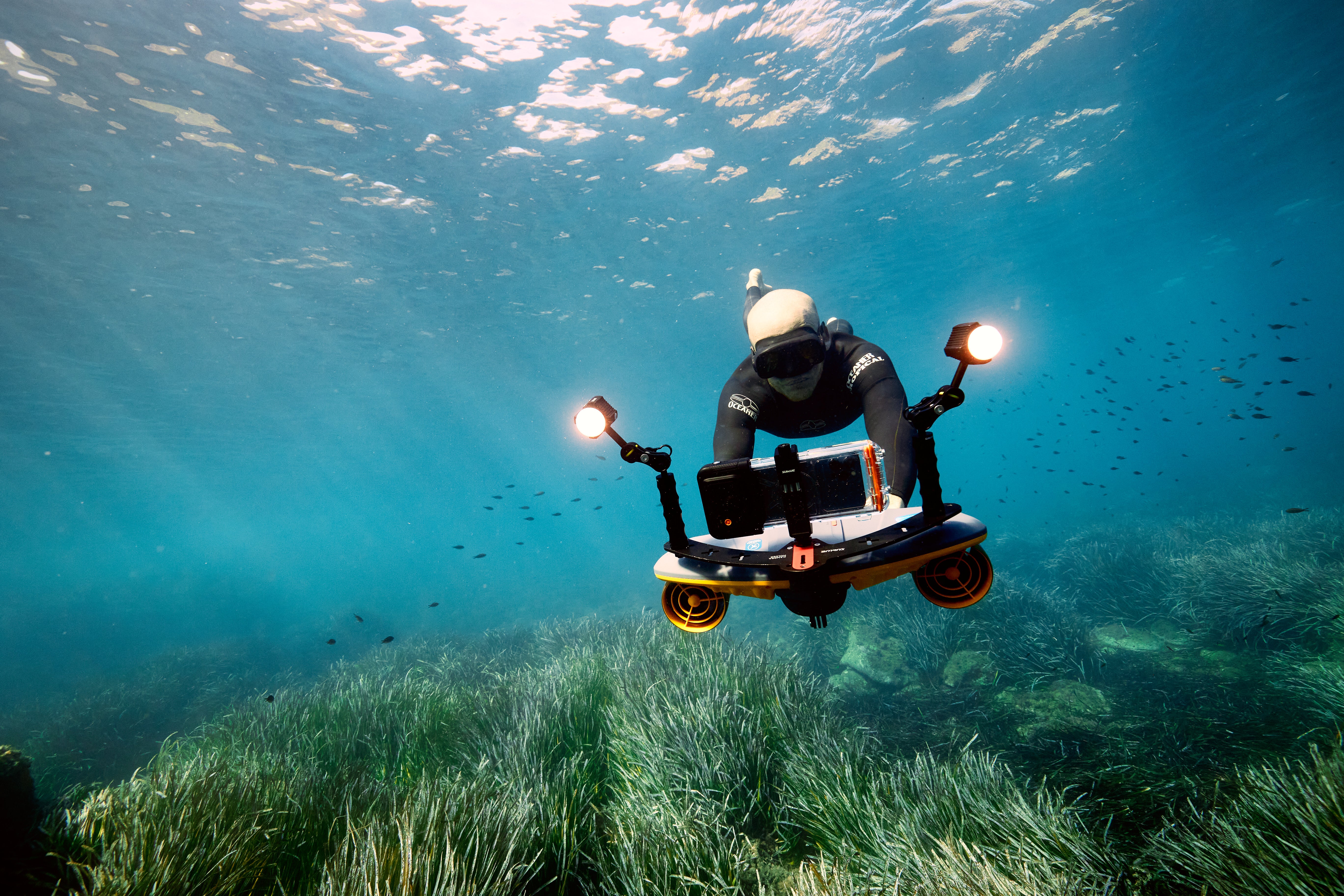 Diver using Sublue scooter with dual LED lights exploring underwater seagrass.