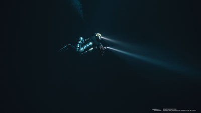 Diver exploring deep waters with two powerful underwater lights.