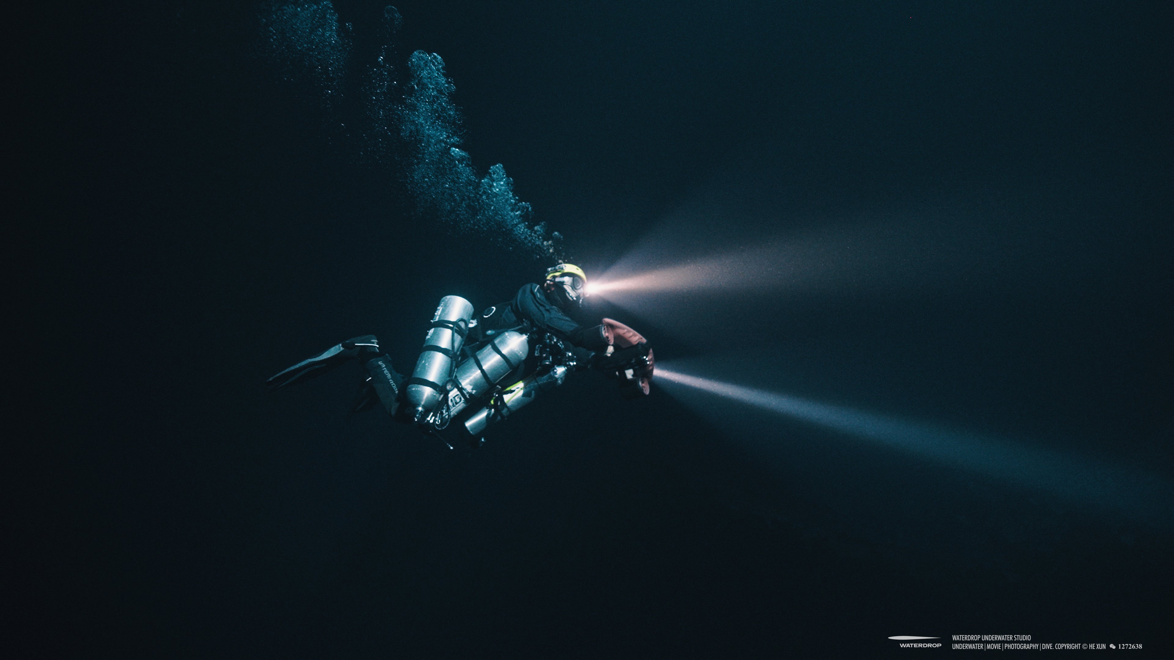 Diver using handheld light for underwater exploration in dark waters