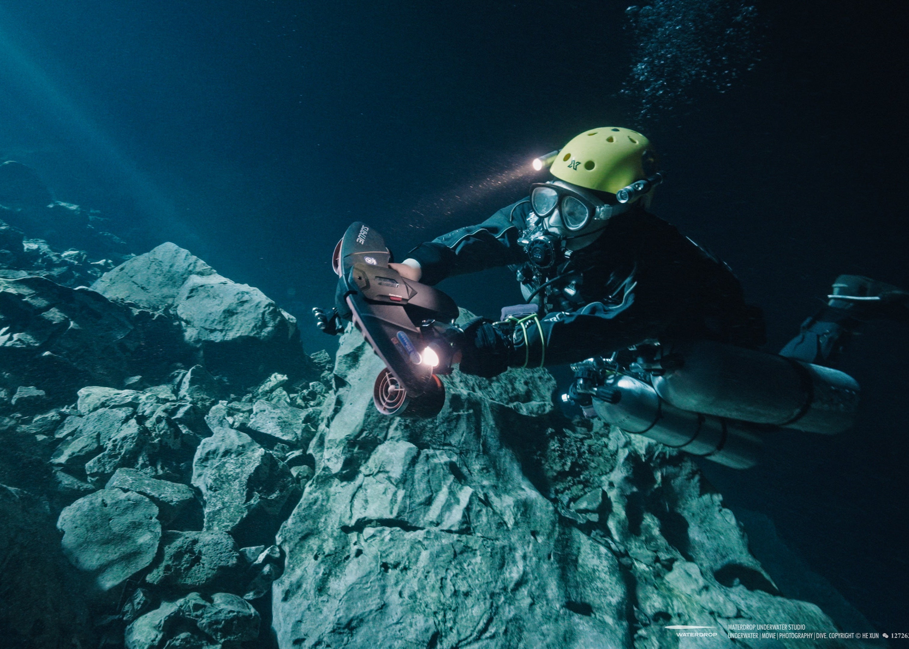 Diver using SUBLUE Navbow scooter in rocky underwater environment.