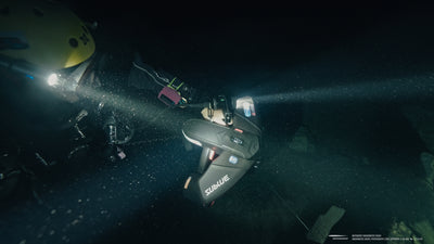 Diver using Navbow+ underwater scooter with powerful lights in dark waters.