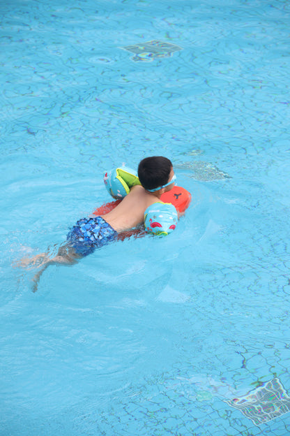 Child swimming with colorful inflatable armbands in a blue swimming pool