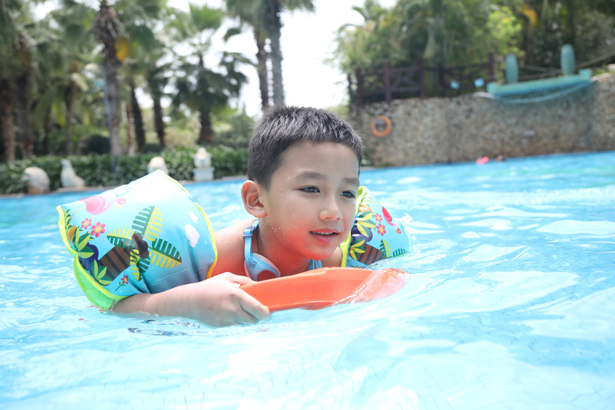 Child enjoying swimming in a blue pool with colorful arm floaties.