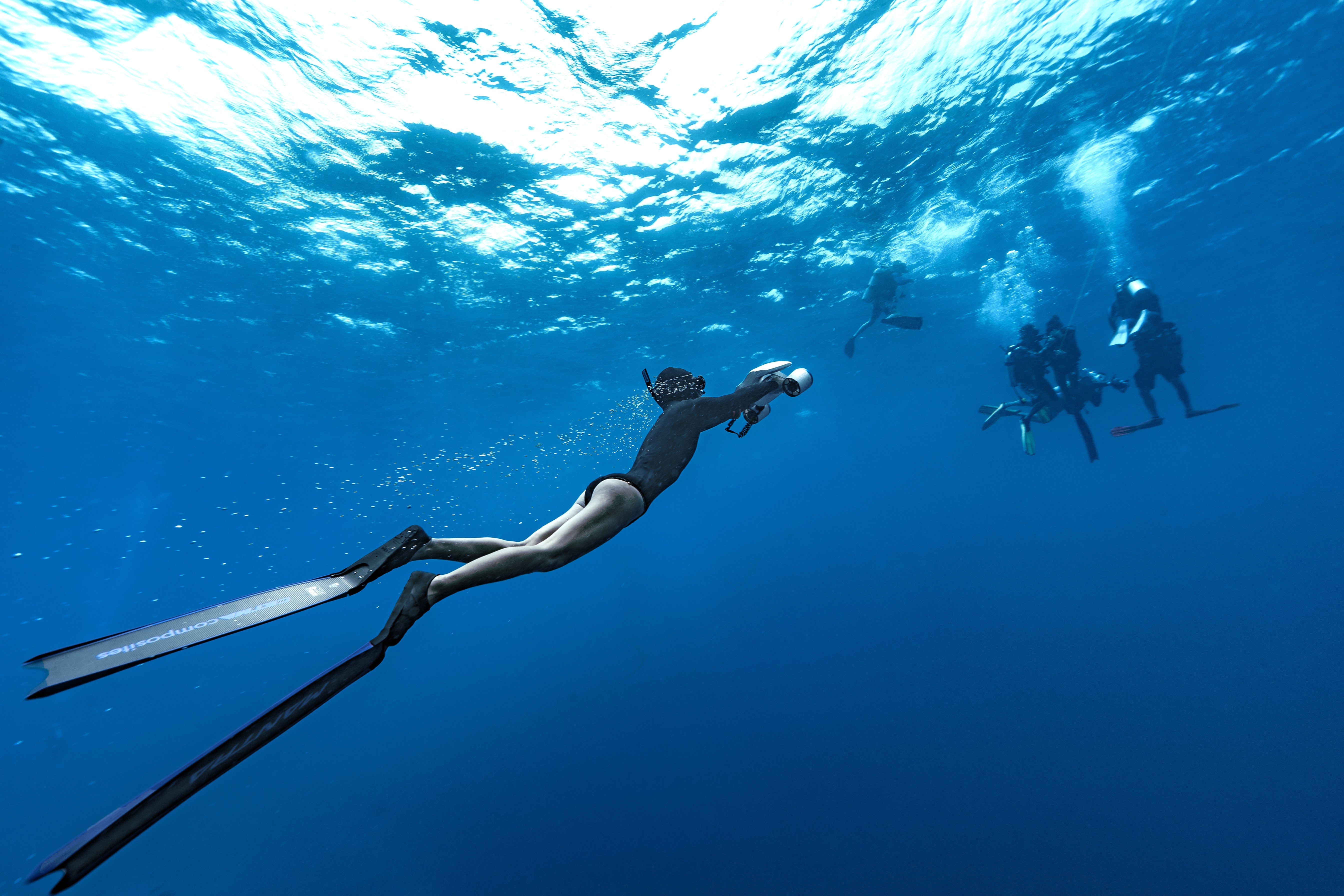 Diver exploring underwater with fins and anti-lost lanyard for safety.