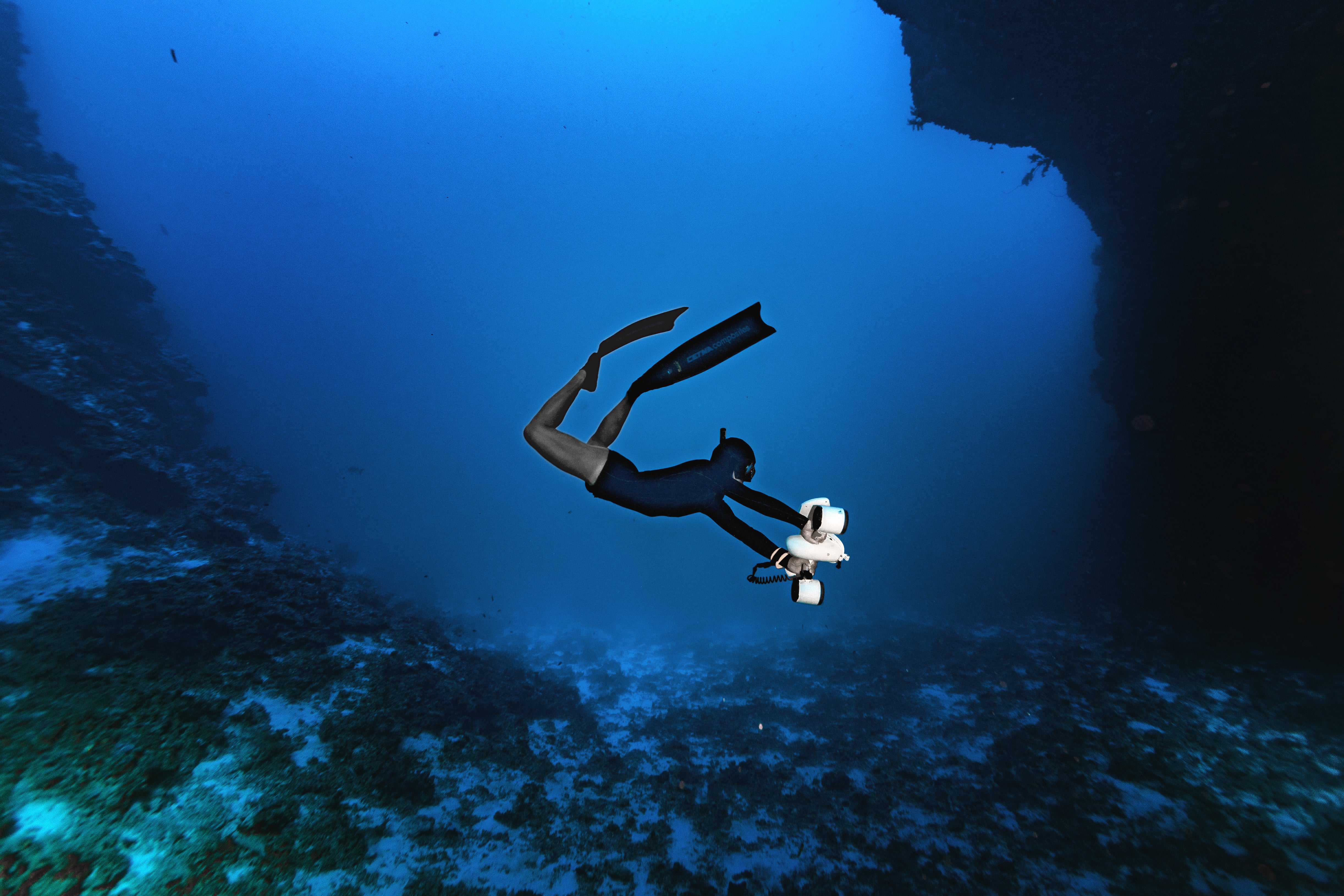 Diver using Sublue underwater scooter in deep blue water.