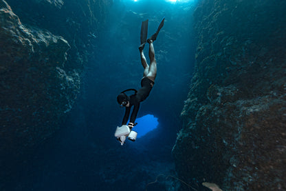 Diver using Sublue underwater scooter in an underwater cave with fins.