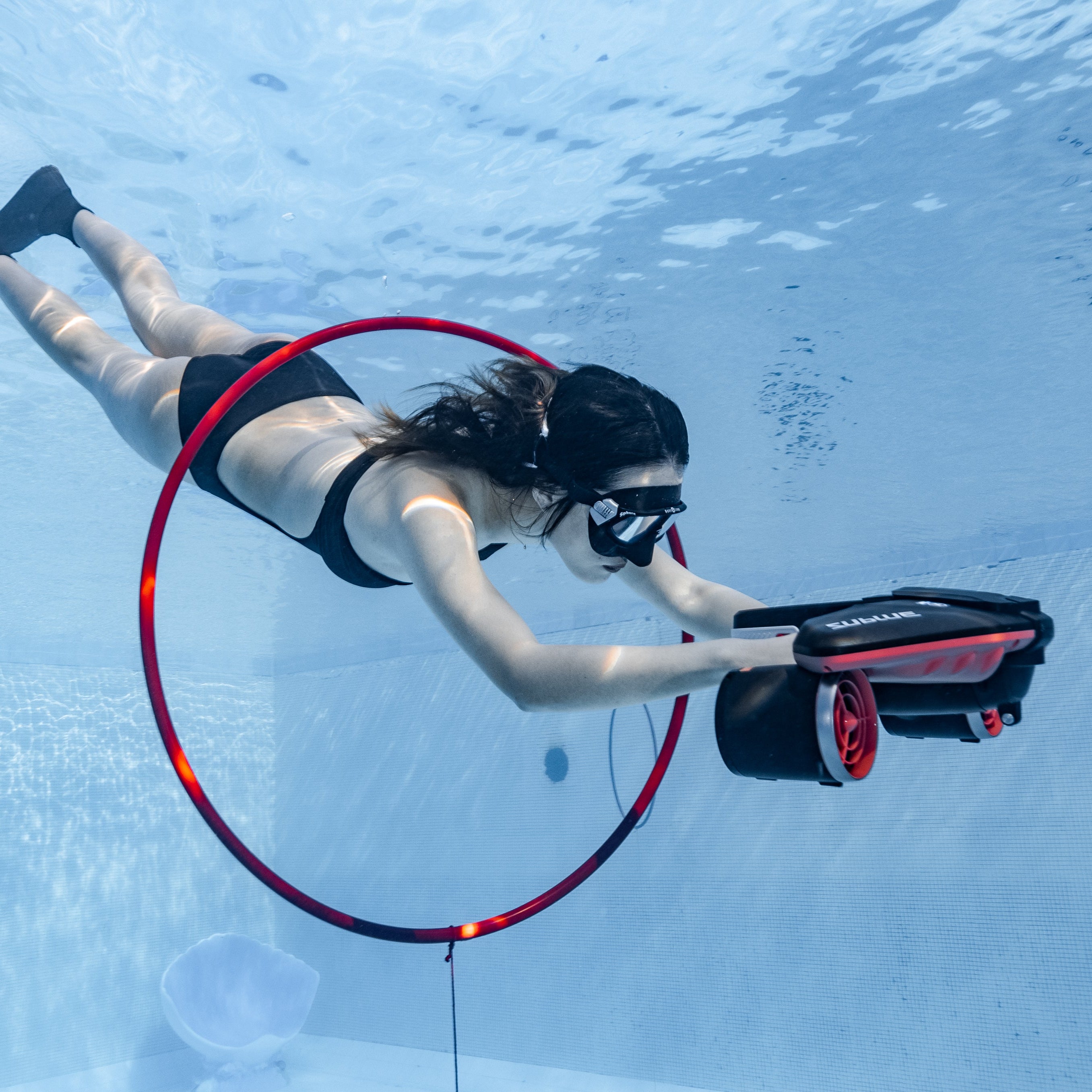 Diver swimming through hoop while using SUBLUE Navbow underwater scooter.