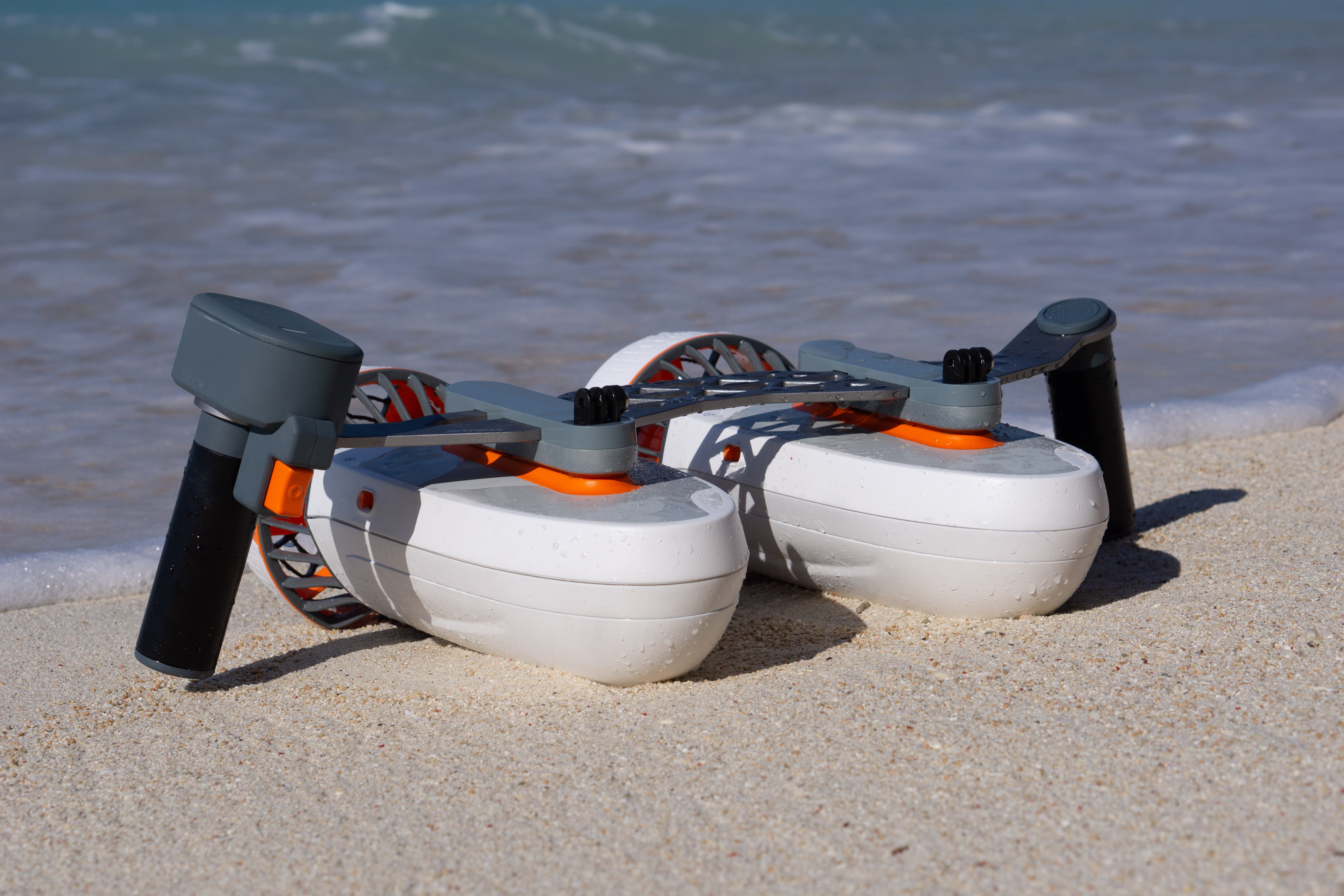 Tini Double-Engine Support Handle connected to underwater scooters on sandy beach.