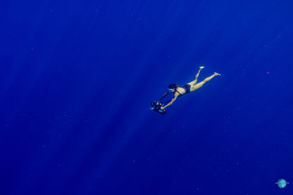 Diver using Sublue underwater scooter in deep blue ocean water.