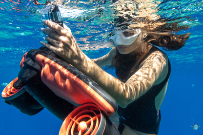 Diver handling Sublue underwater scooter with Diving Cross Strap in clear water.