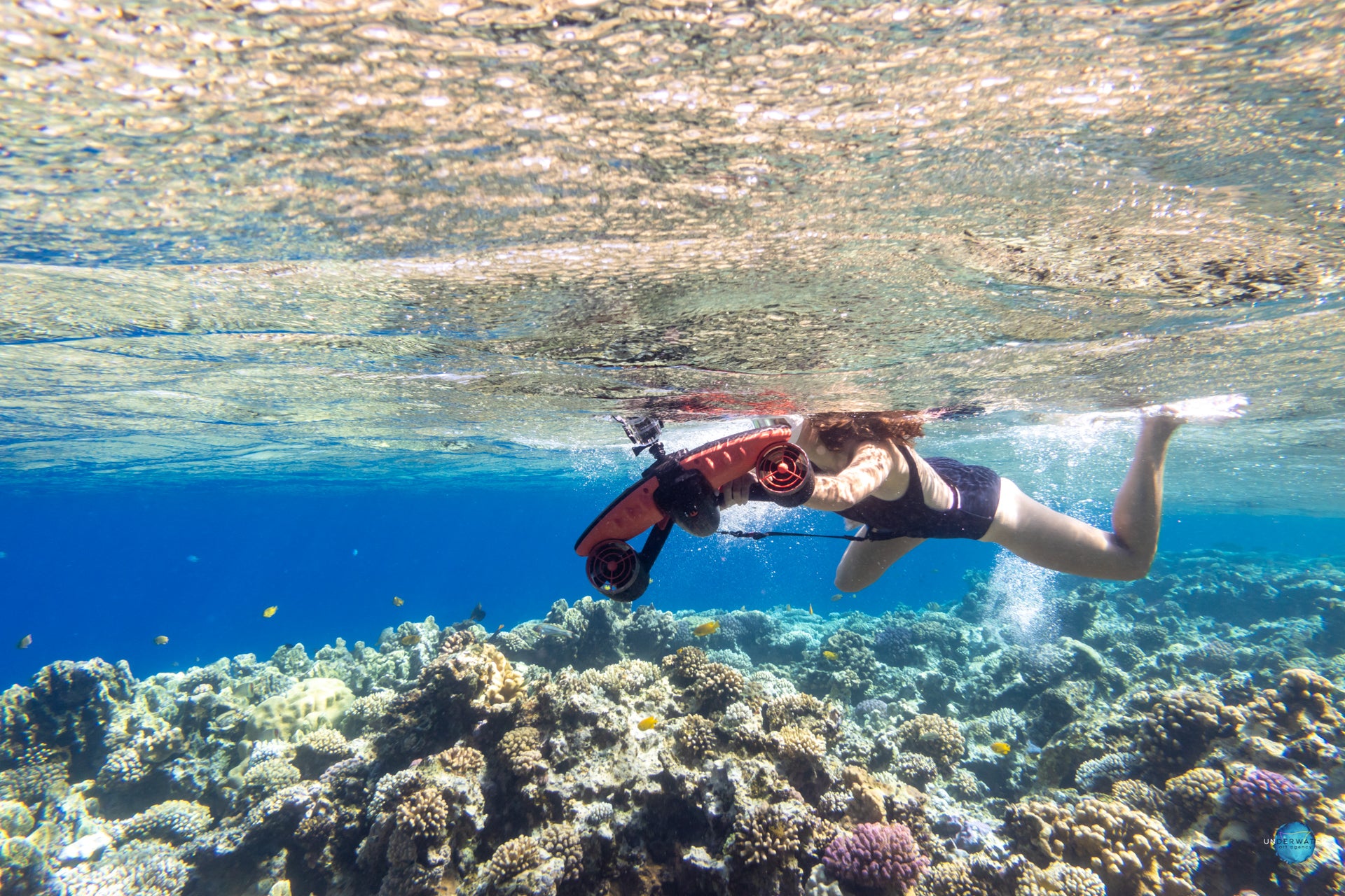 Diver using Sublue underwater scooter in a vibrant coral reef.