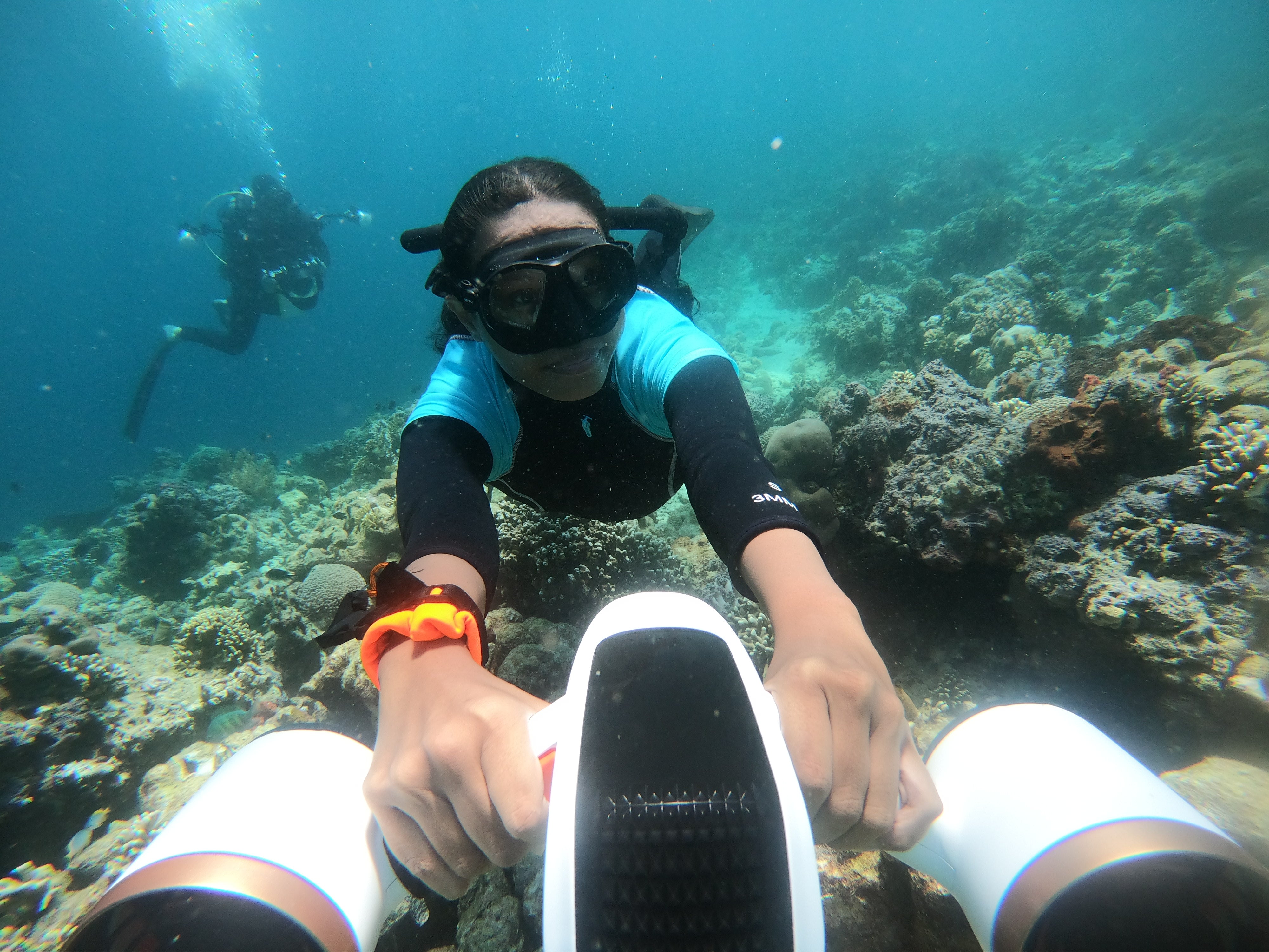 Child gliding underwater with SUBLUE MixPro scooter near colorful coral reef.