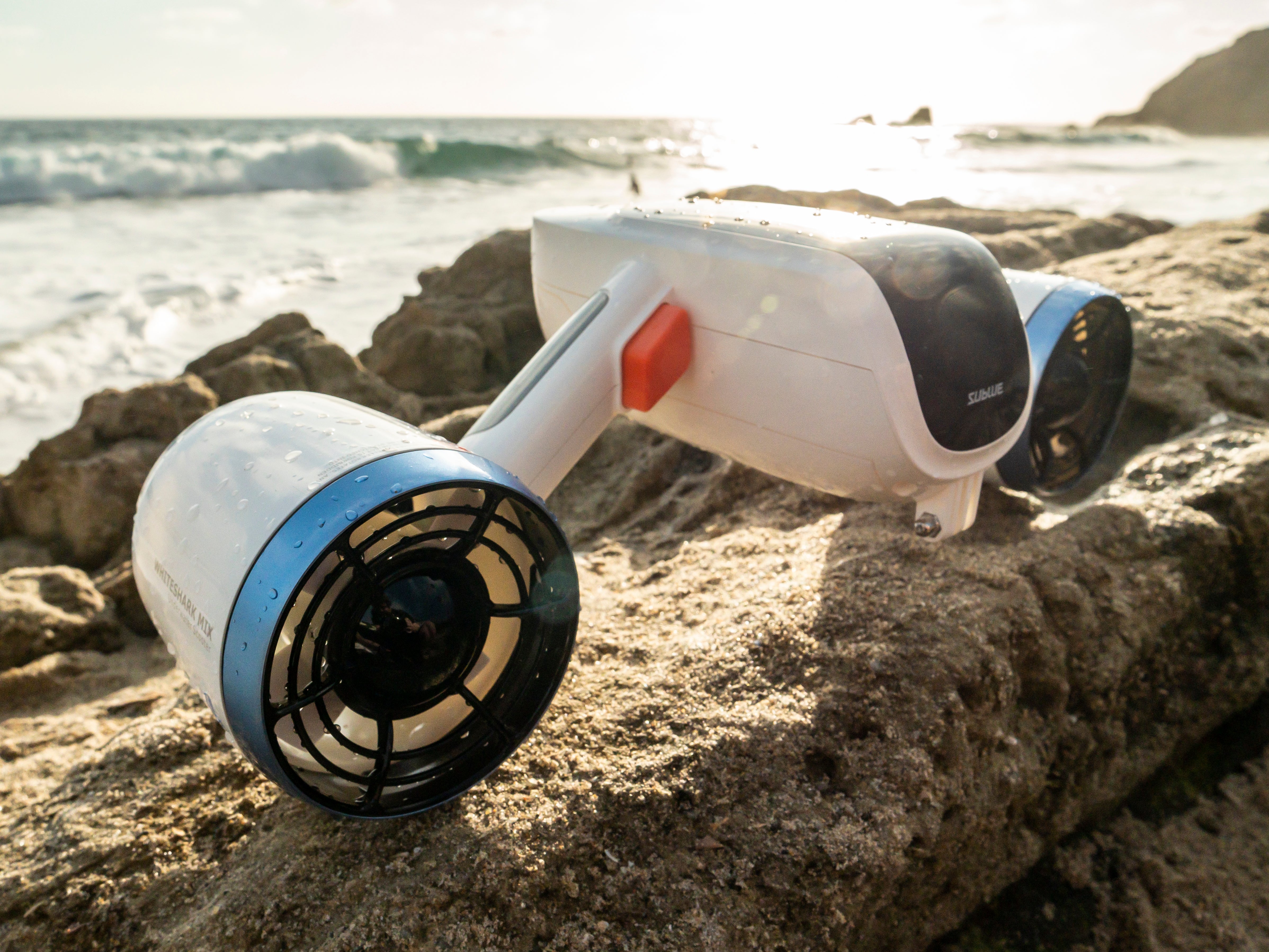 Sublue Mix underwater scooter on rocks with ocean view and dual motors.