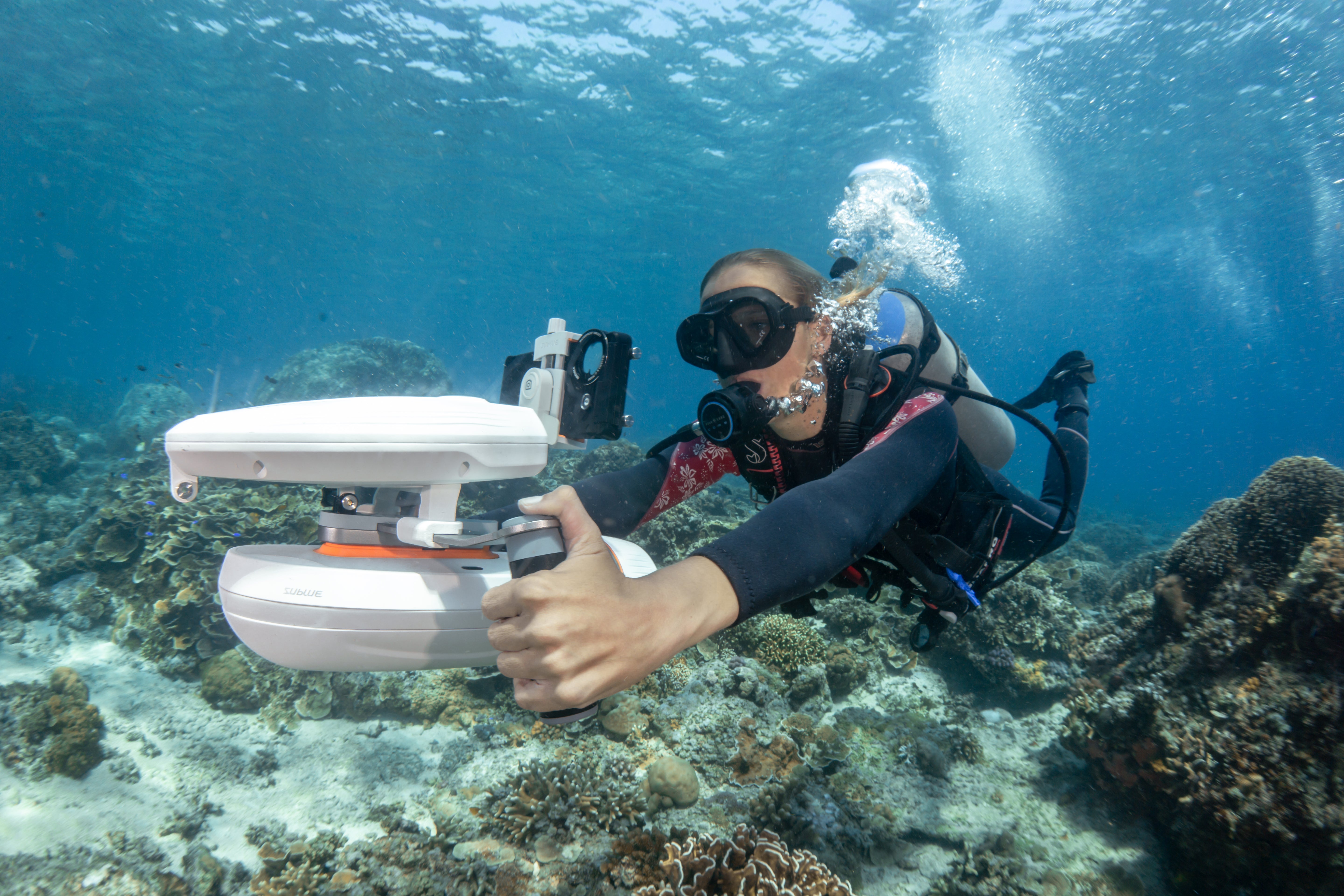 Diver using Sublue H1 waterproof phone case with scooter for underwater photography