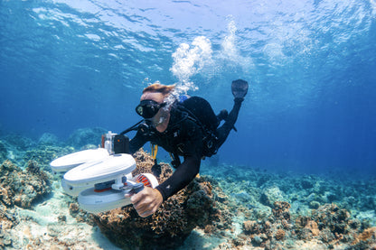 Diver with Tini Floater attached to scooter exploring coral reefs underwater.