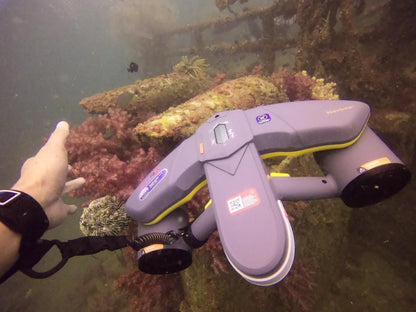 Diver's hand pointing at submerged wreck using Sublue scooter with anti-lost lanyard.