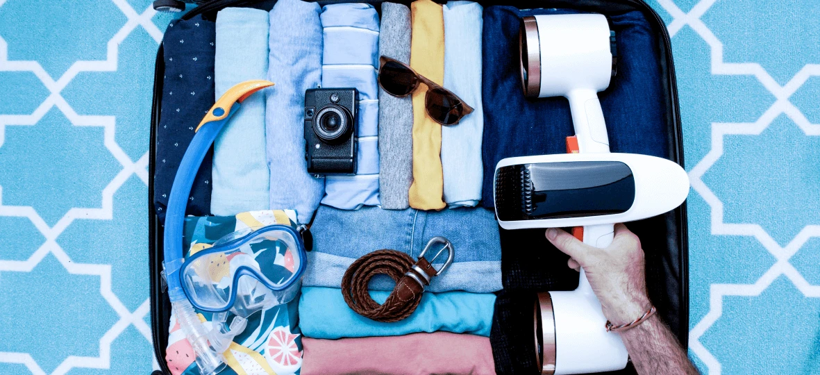a hand holding a device next to clothes and sunglasses